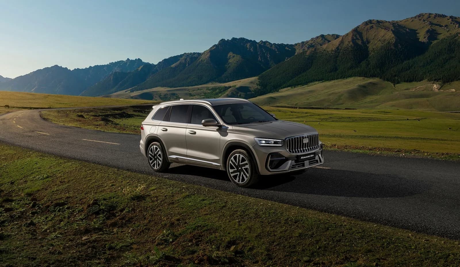 Geely Monjaro EM-i plug-in hybrid SUV in a gold-grey finish, front three-quarter view on a mountain road