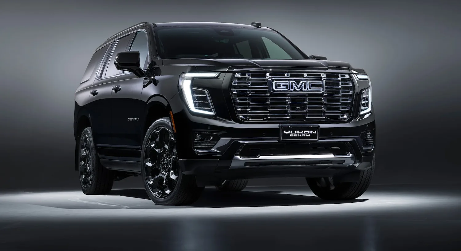 GMC Yukon Denali Signature Black in Onyx Black with black 24-inch wheels, front three-quarter studio view