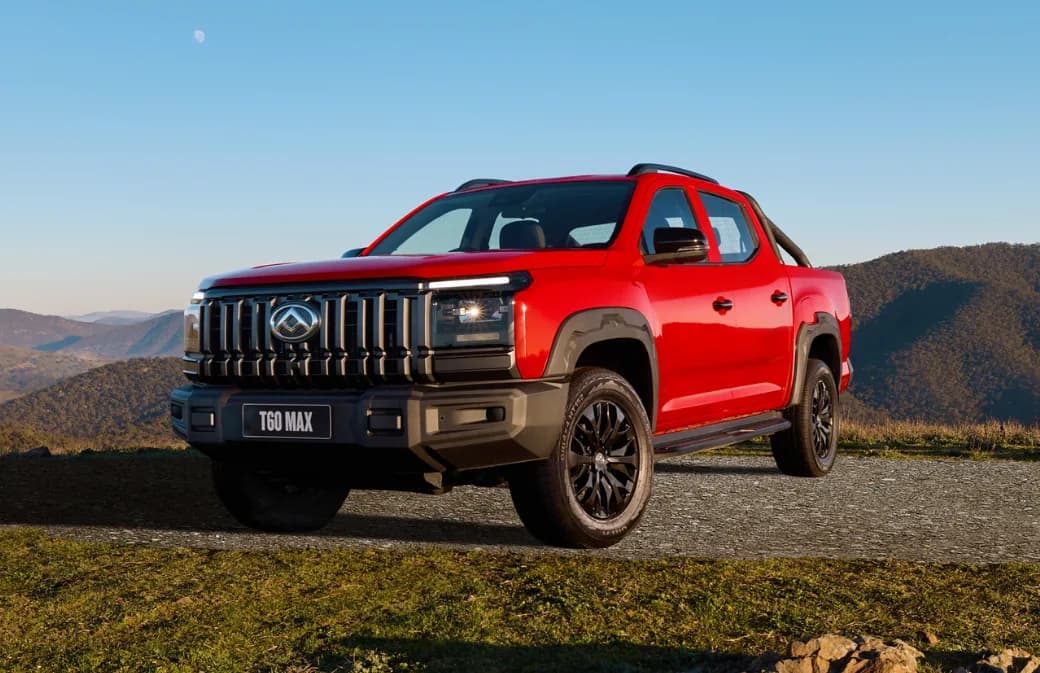 Red 2027 LDV T60 MAX Luxe dual-cab ute with sports bar and black wheel arches, front three-quarter view on a gravel hilltop