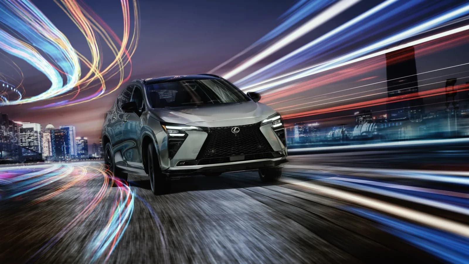 Upgraded Lexus NX in silver, front three-quarter view, driving at night past city lights