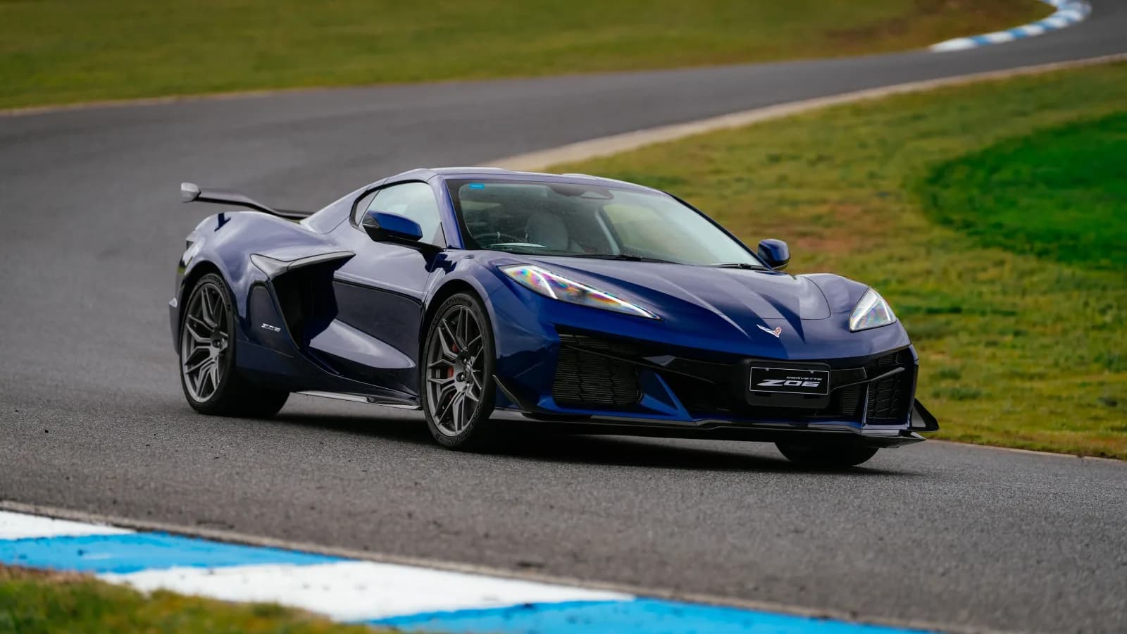 2027 Chevrolet Corvette Z06 in blue, front three-quarter view on a racing circuit