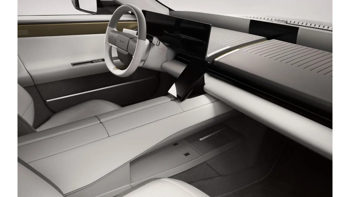 Jaguar Type 01 interior in the Light Story theme, showing the brass-coloured centre spine, the 24-inch OLED display and the panoramic roof