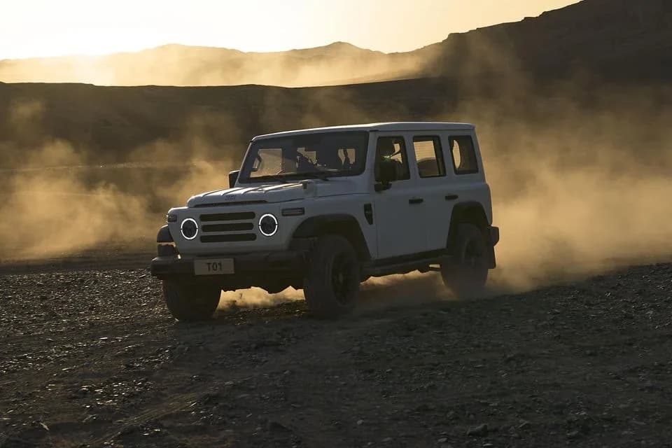 212 T01 boxy off-roader in white kicking up dust on a desert track