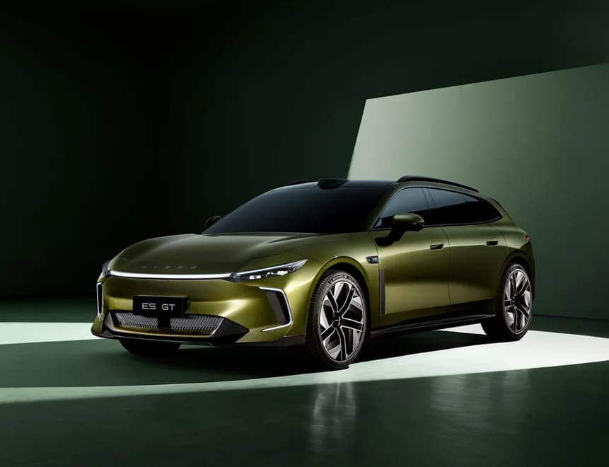 Olive-green Exlantix ES GT shooting brake with a full-width front light bar and ES GT plate, front three-quarter view in a dark studio