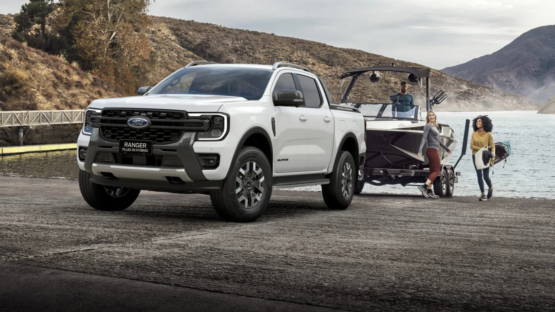 Ford Ranger PHEV towing a ski boat at a lake boat ramp, demonstrating the 3,500 kg braked tow rating