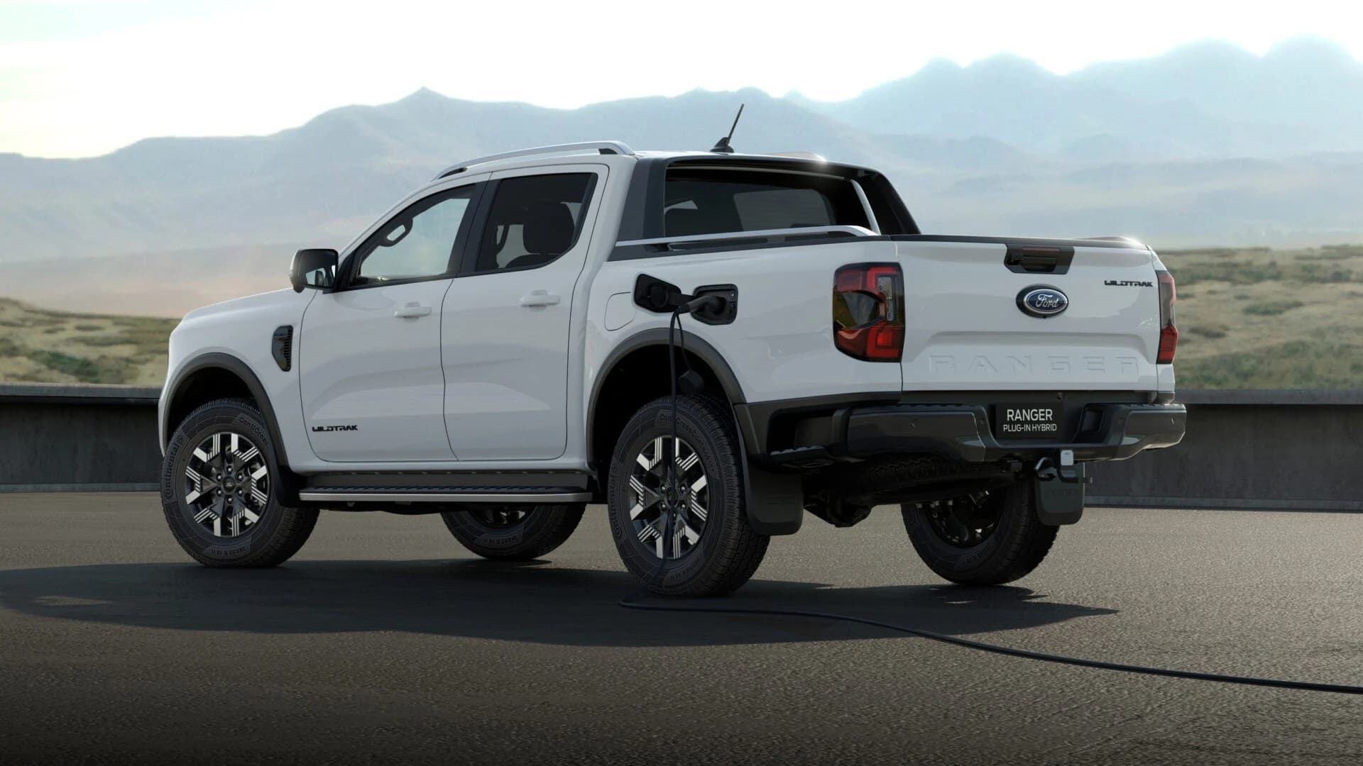 Ford Ranger PHEV Wildtrak charging via the rear-mounted charge port, rear three-quarter view