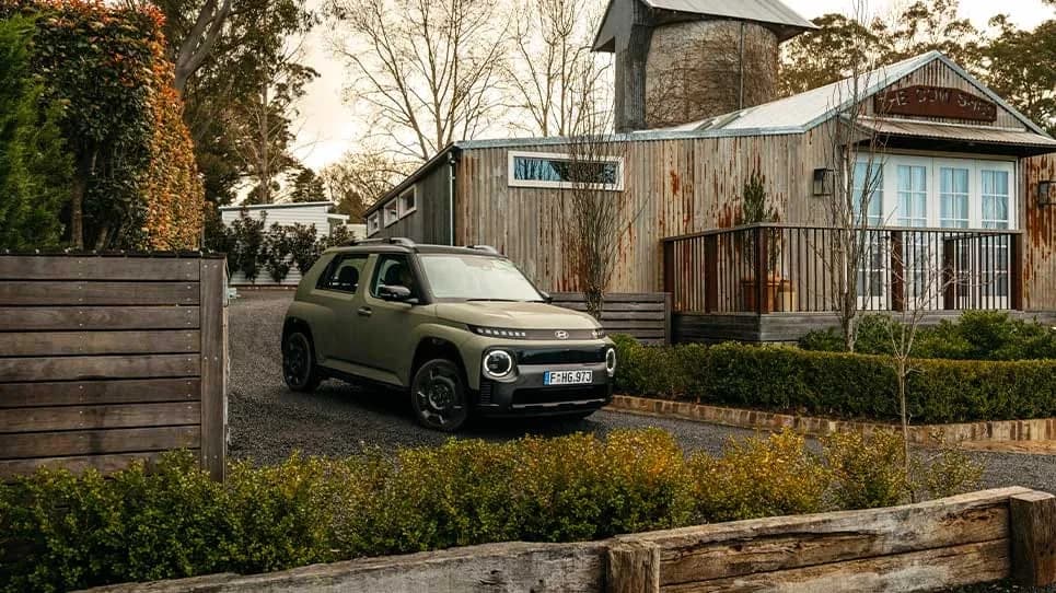 Hyundai Inster in khaki green parked in a gravel driveway