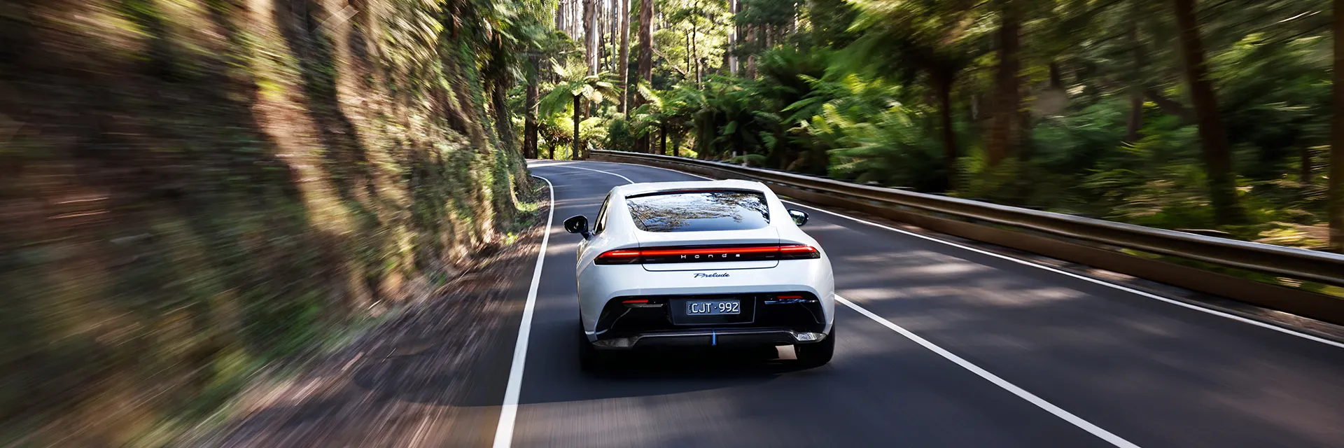 2026 Honda Prelude e:HEV rear three-quarter driving through Australian forest road