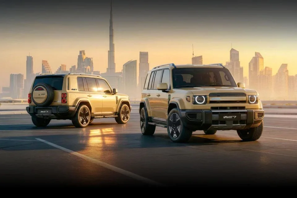 Two iCaur V27 boxy SUVs in tan colour photographed against a Dubai cityscape