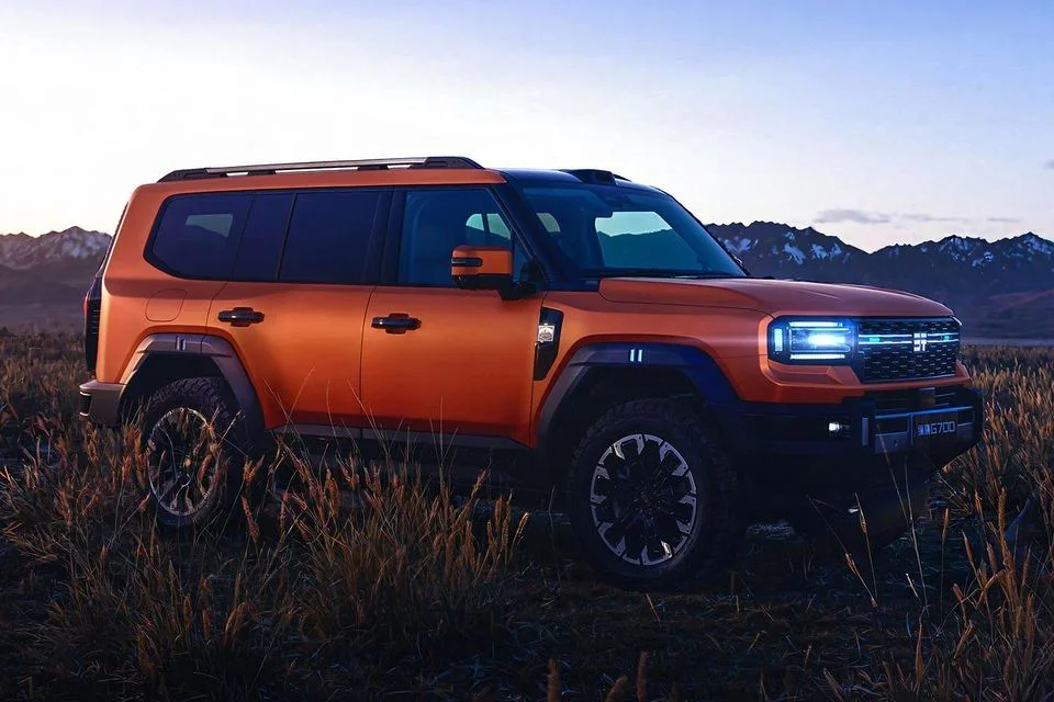 Jetour G700 large body-on-frame SUV in orange parked in a grassy mountain landscape at golden hour