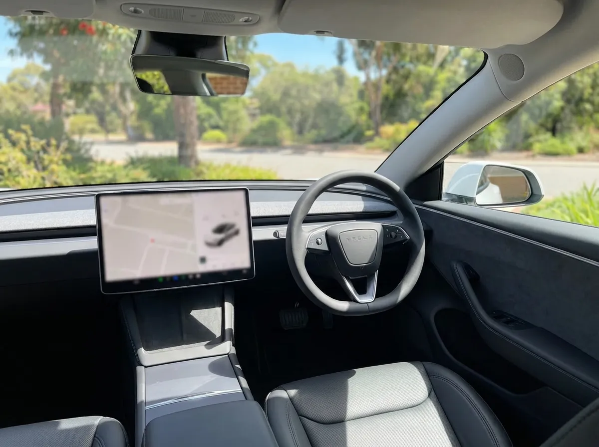Tesla Model 3 Highland interior showing 15.4-inch touchscreen, steering wheel, and minimalist dashboard from driver's seat